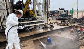 Technician cleaning industrial equipment on a rig site